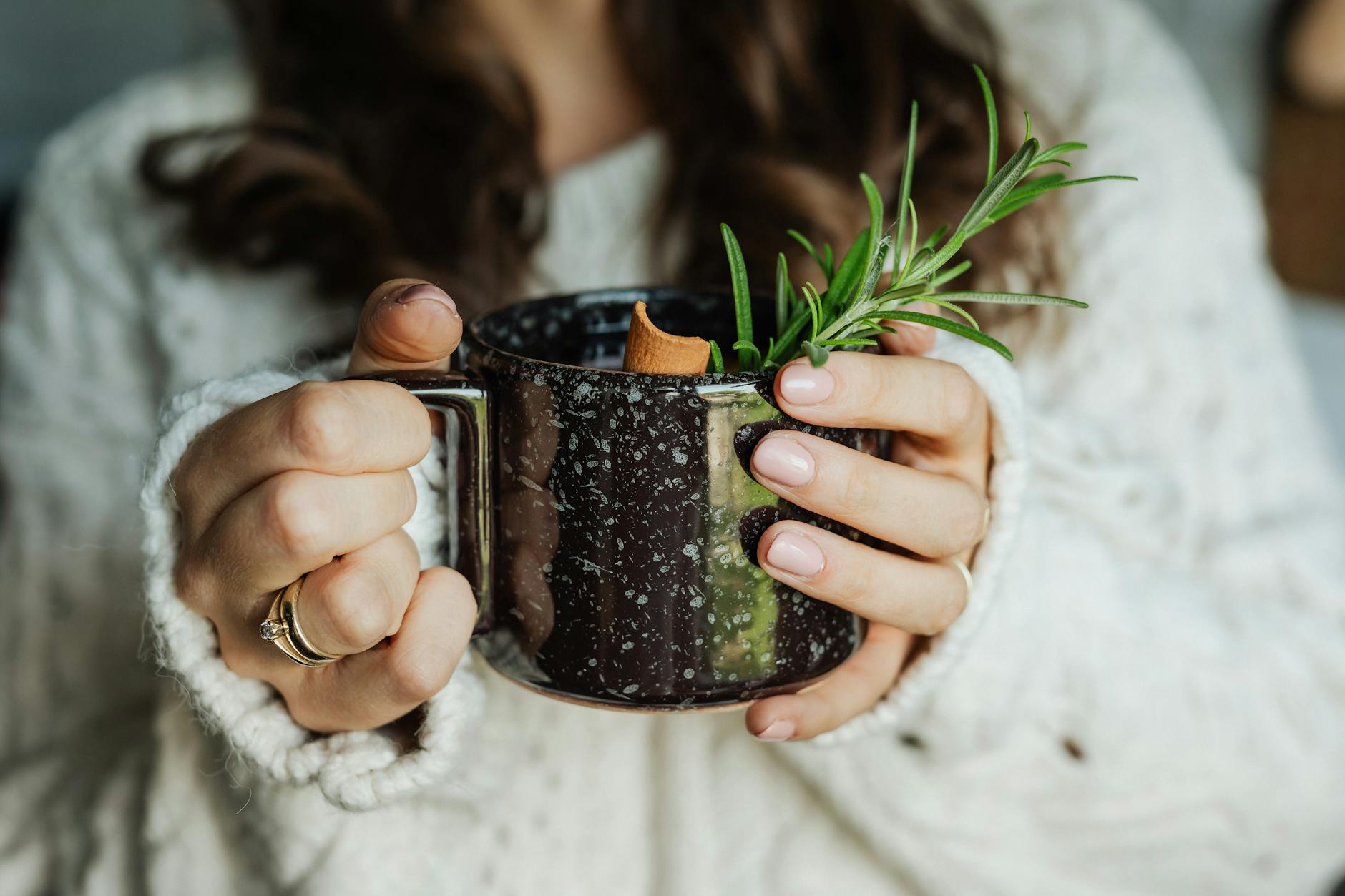 Kobieta w ciepłym swetrze trzyma kubek z ziołową herbatą jesienią