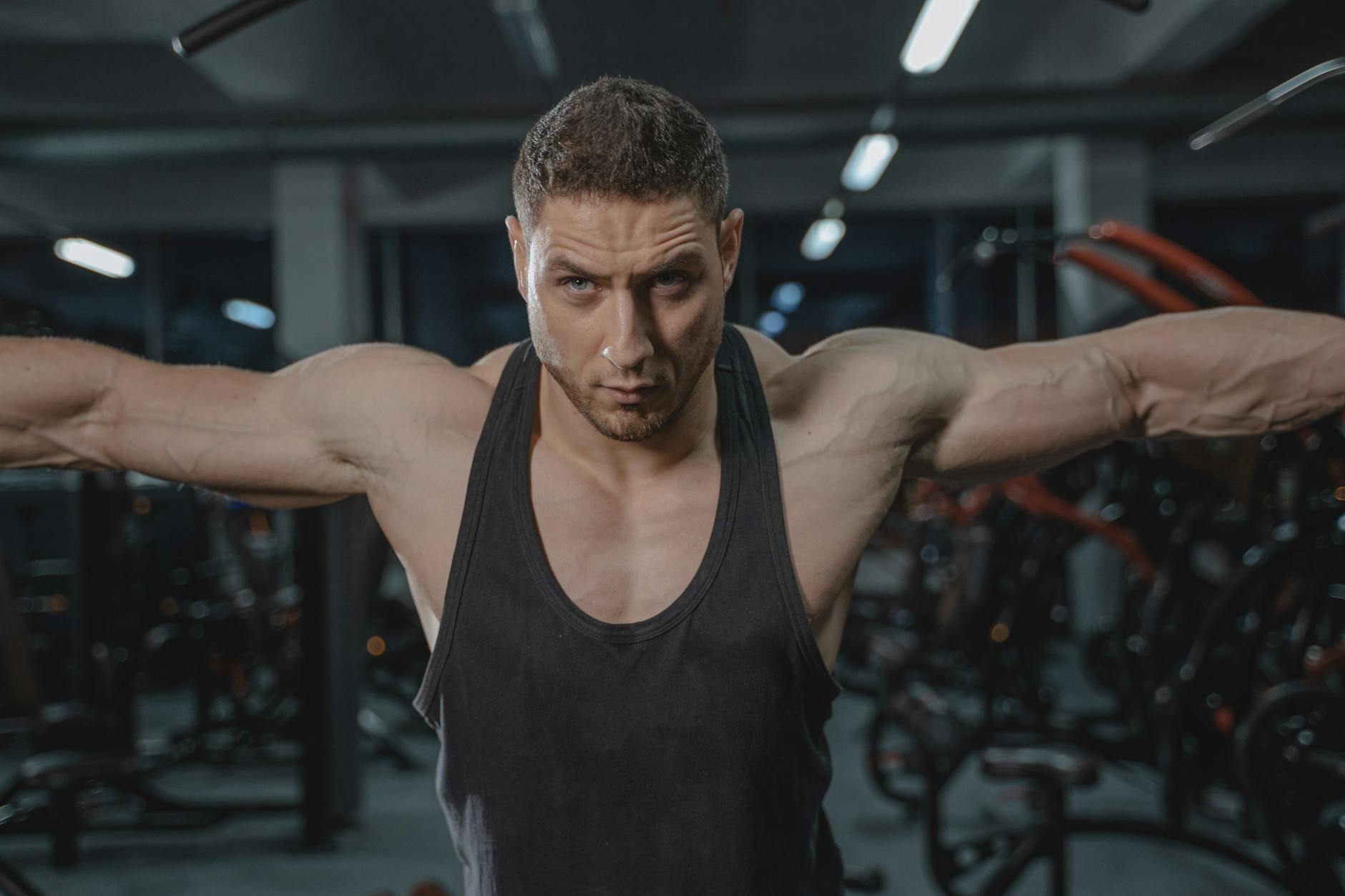 Skupiony mężczyzna w sportowym stroju ćwiczy barki na siłowni