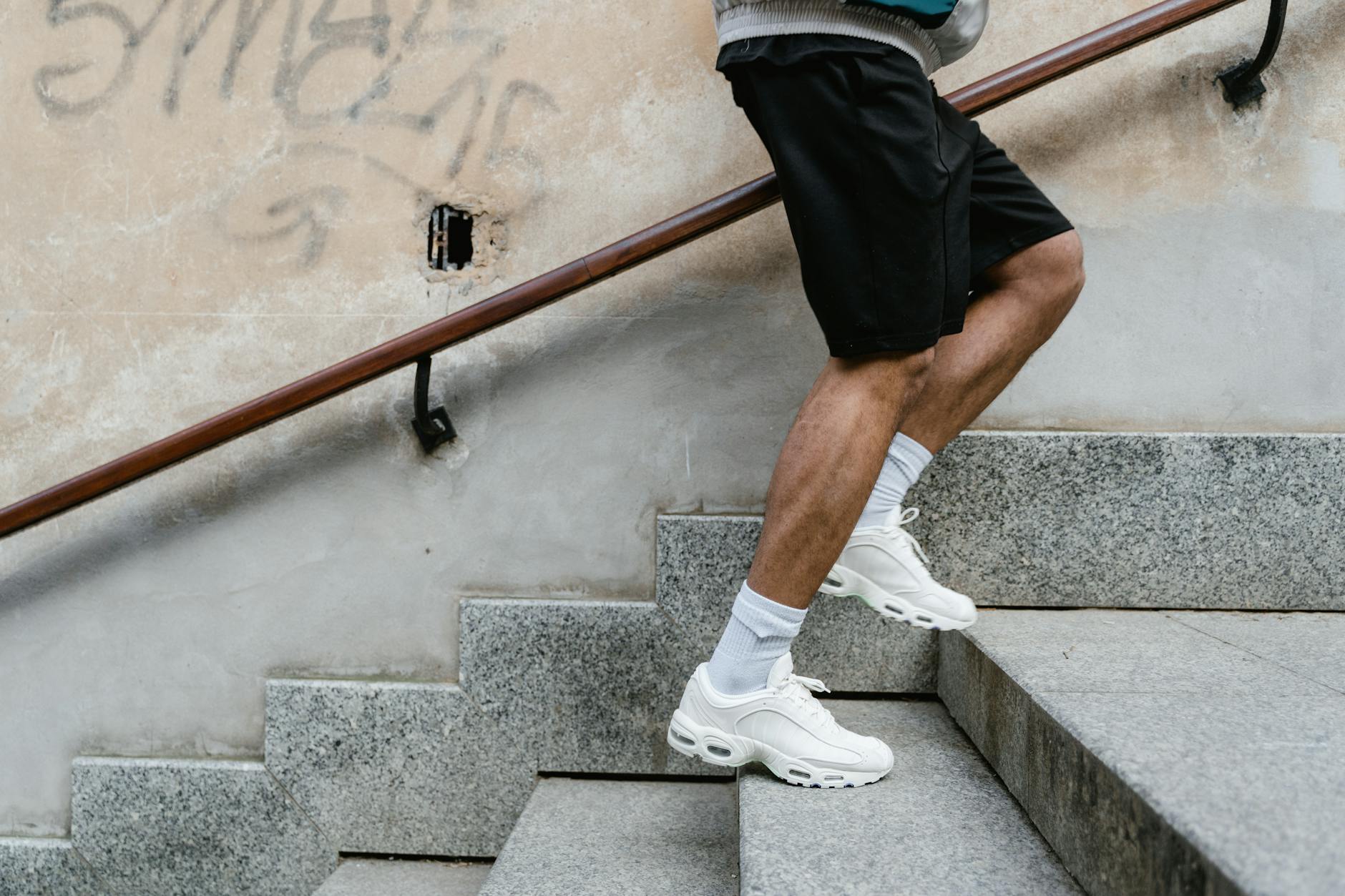 Mężczyzna w sportowym stroju biegnie po schodach na zewnątrz