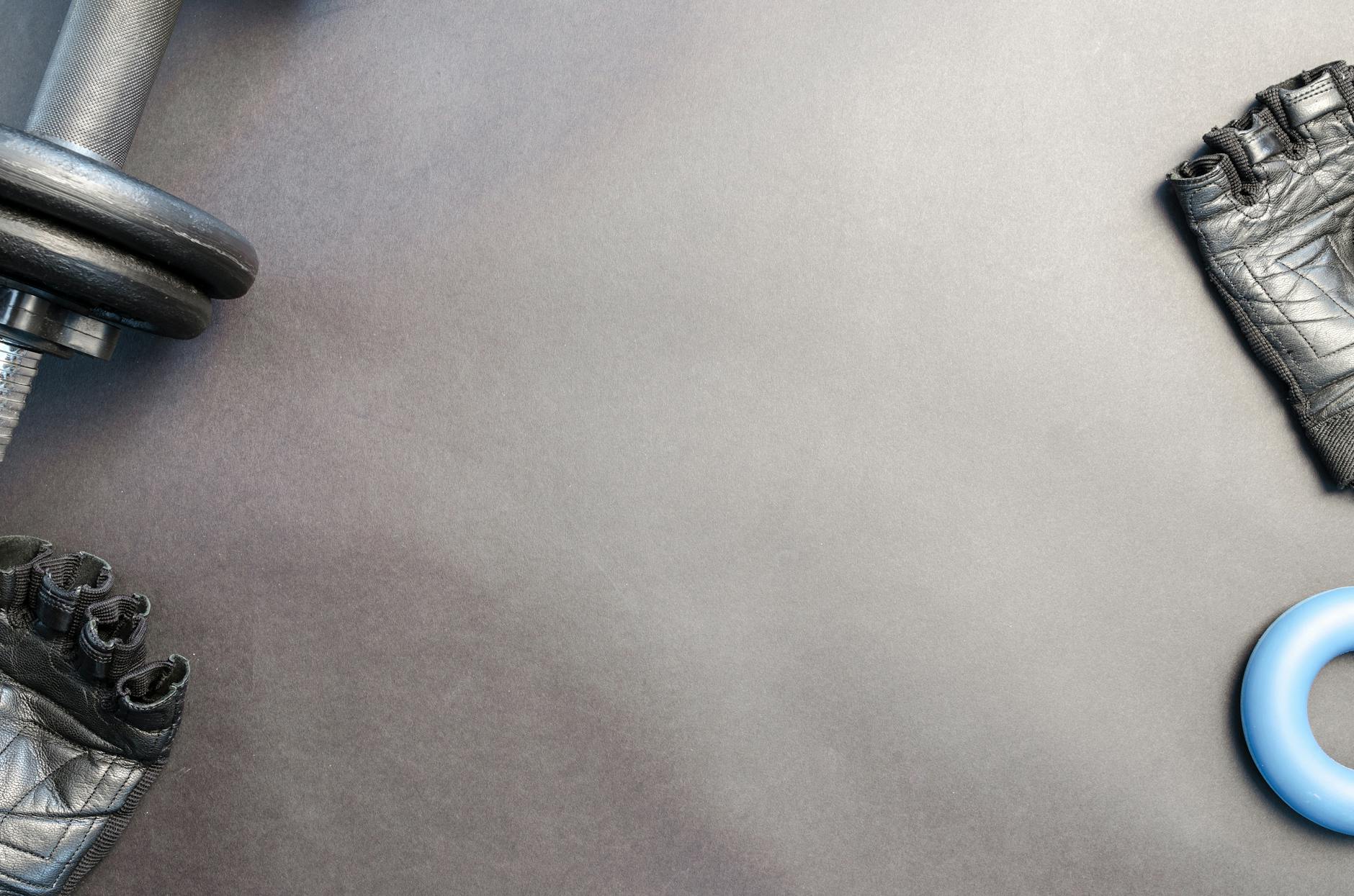 Płaskie ujęcie hantla, rękawic i ringa treningowego na jasnym tle