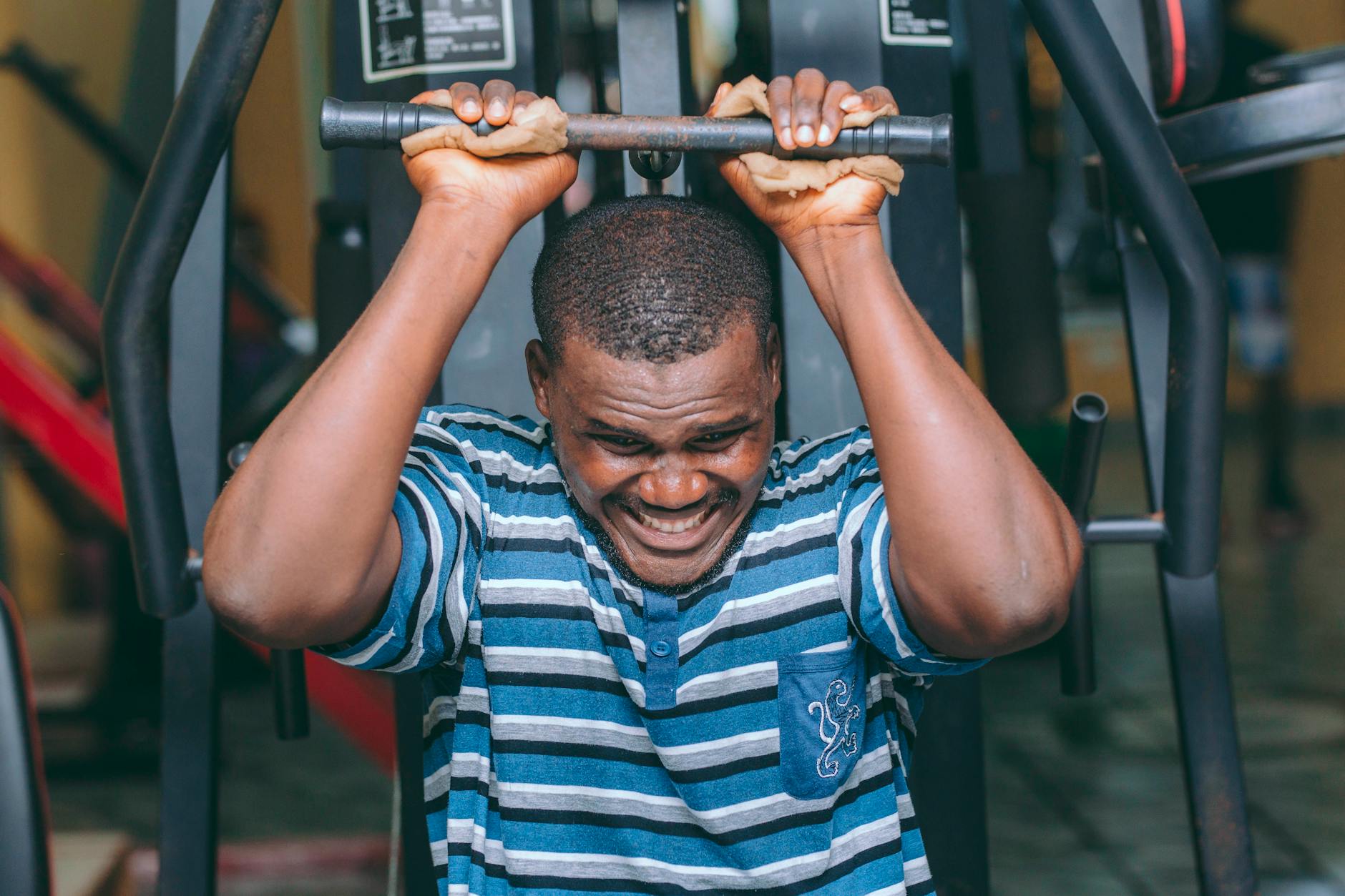 Czarnoskóry mężczyzna ćwiczy intensywnie na maszynie siłowej w siłowni