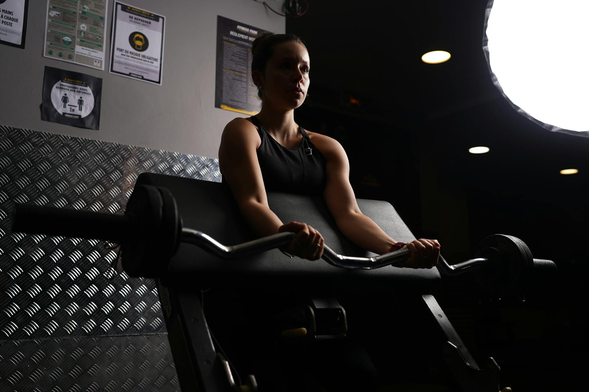 Kobieta w paryskiej siłowni ćwiczy technikę martwego ciągu ze sztangą