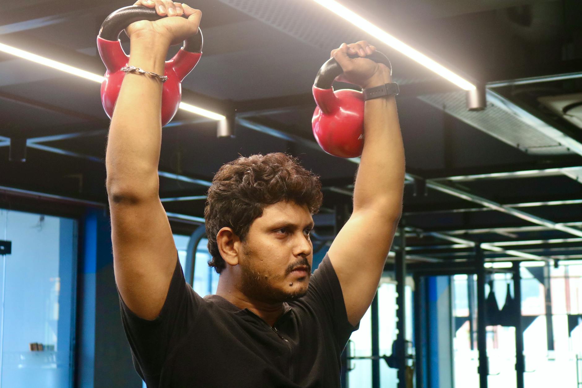 Mężczyzna ćwiczy z kettlebellami w nowoczesnej siłowni