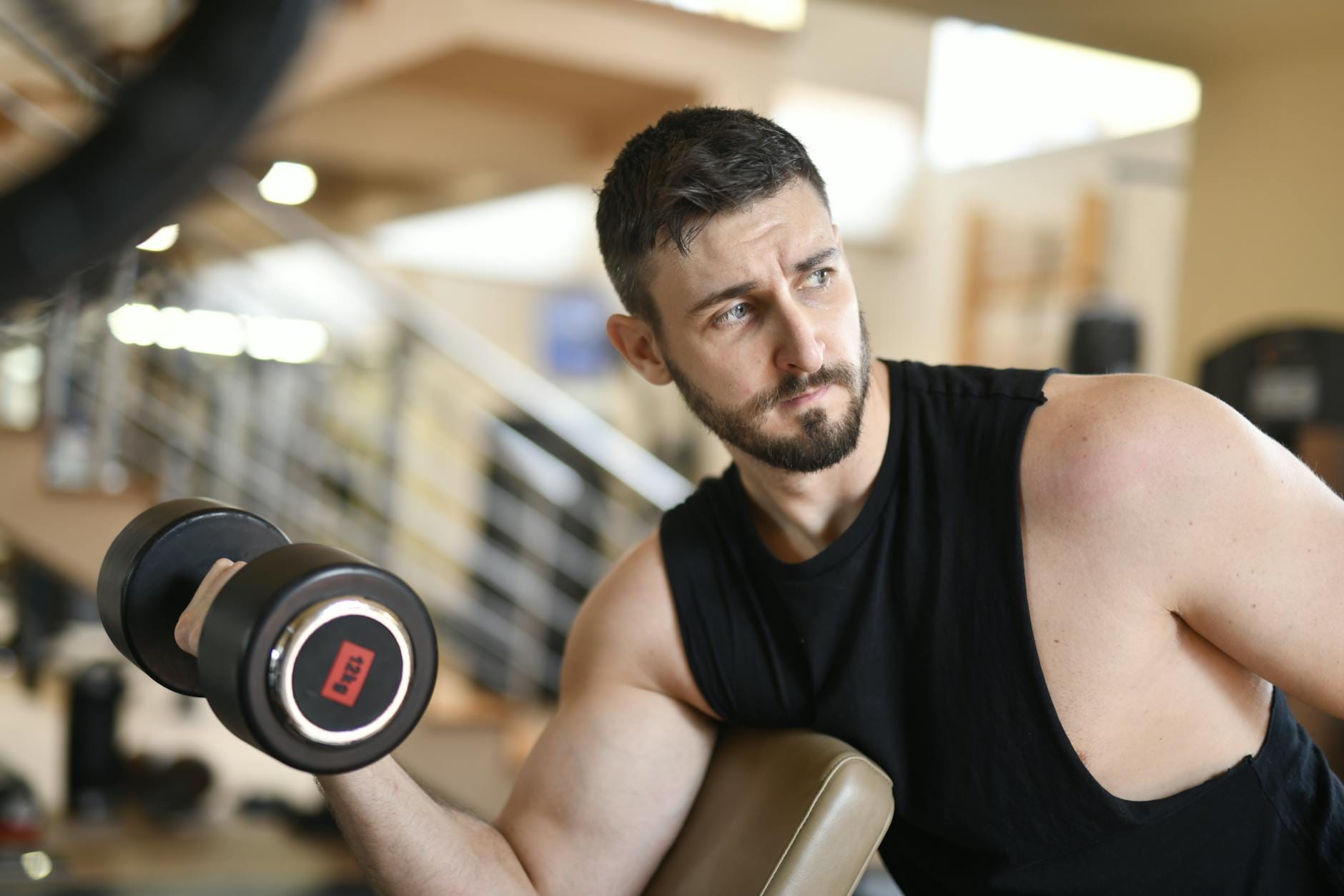 Mężczyzna na siłowni unosi hantel, trenując biceps