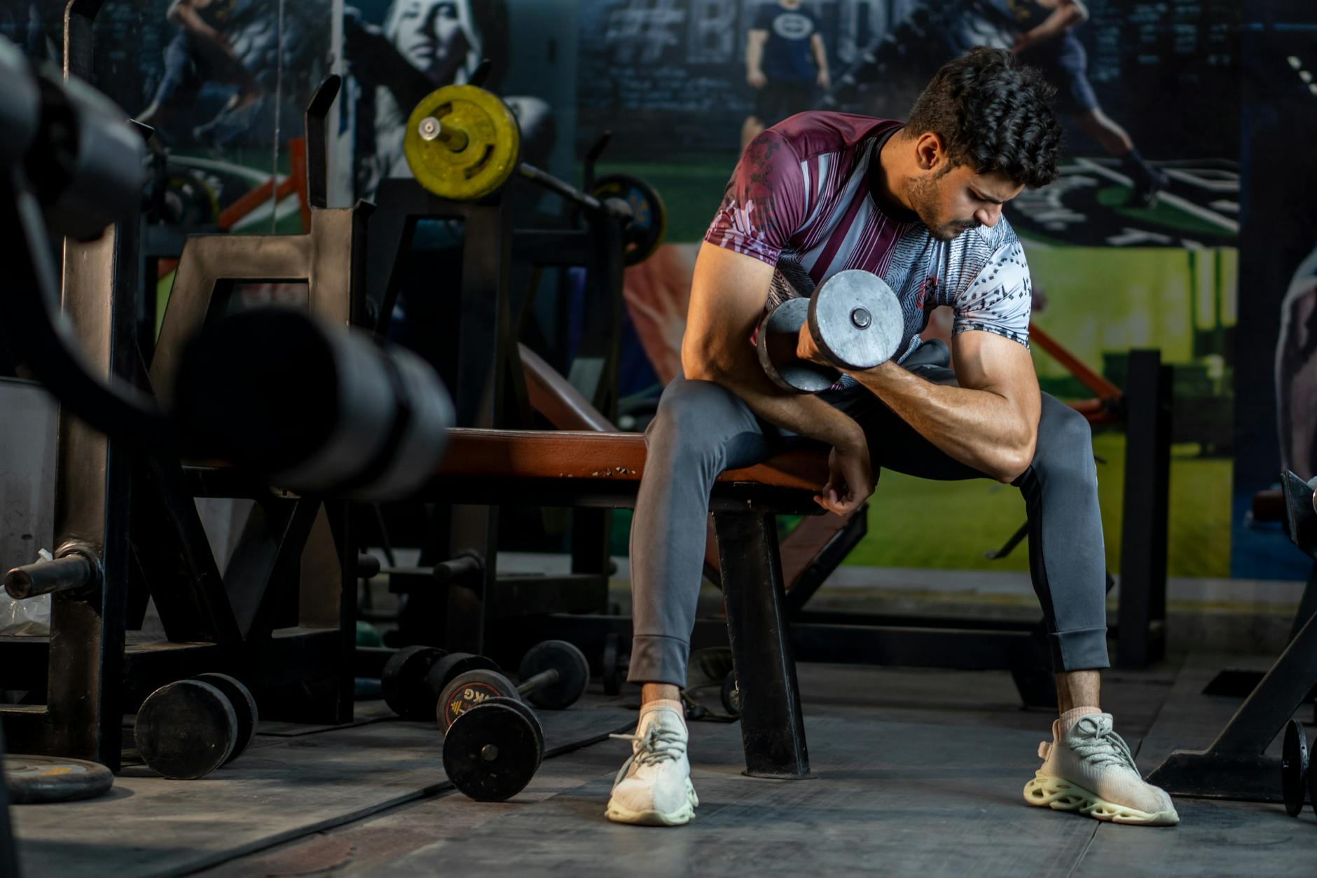 Mężczyzna na siłowni wykonuje uginanie ramion z hantlą na biceps