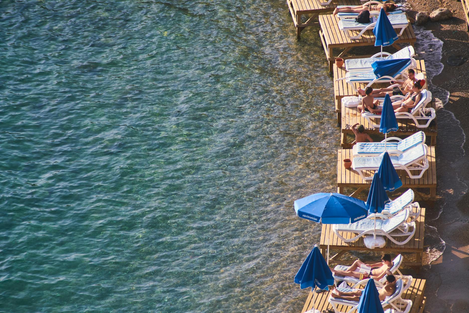 Turyści relaksujący się na drewnianych pomostach przy plaży w Antalyi