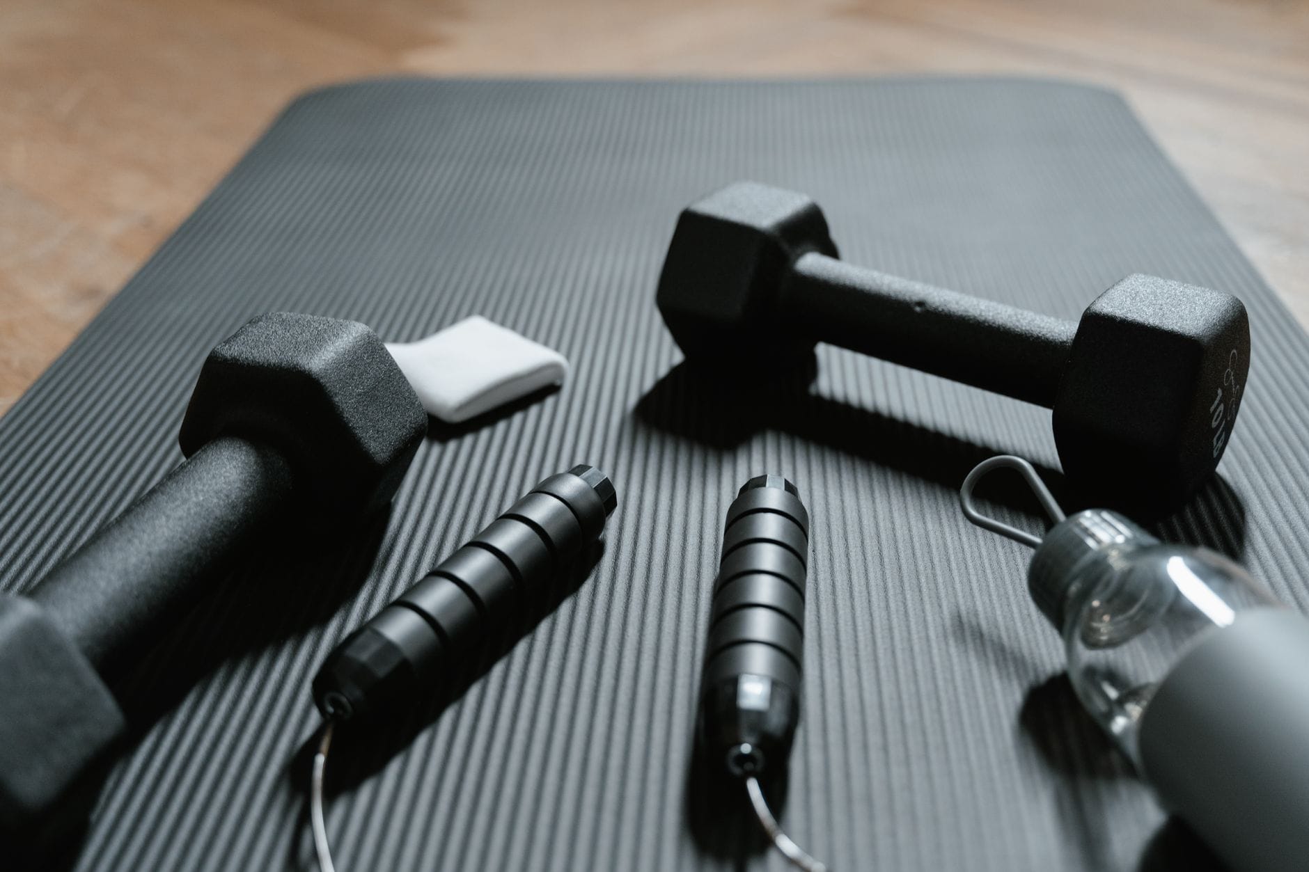 Jak poprawić VO2 max bez biegania? Trening dla zabieganych Hantle, skakanka i butelka wody na macie do domowego treningu cardio