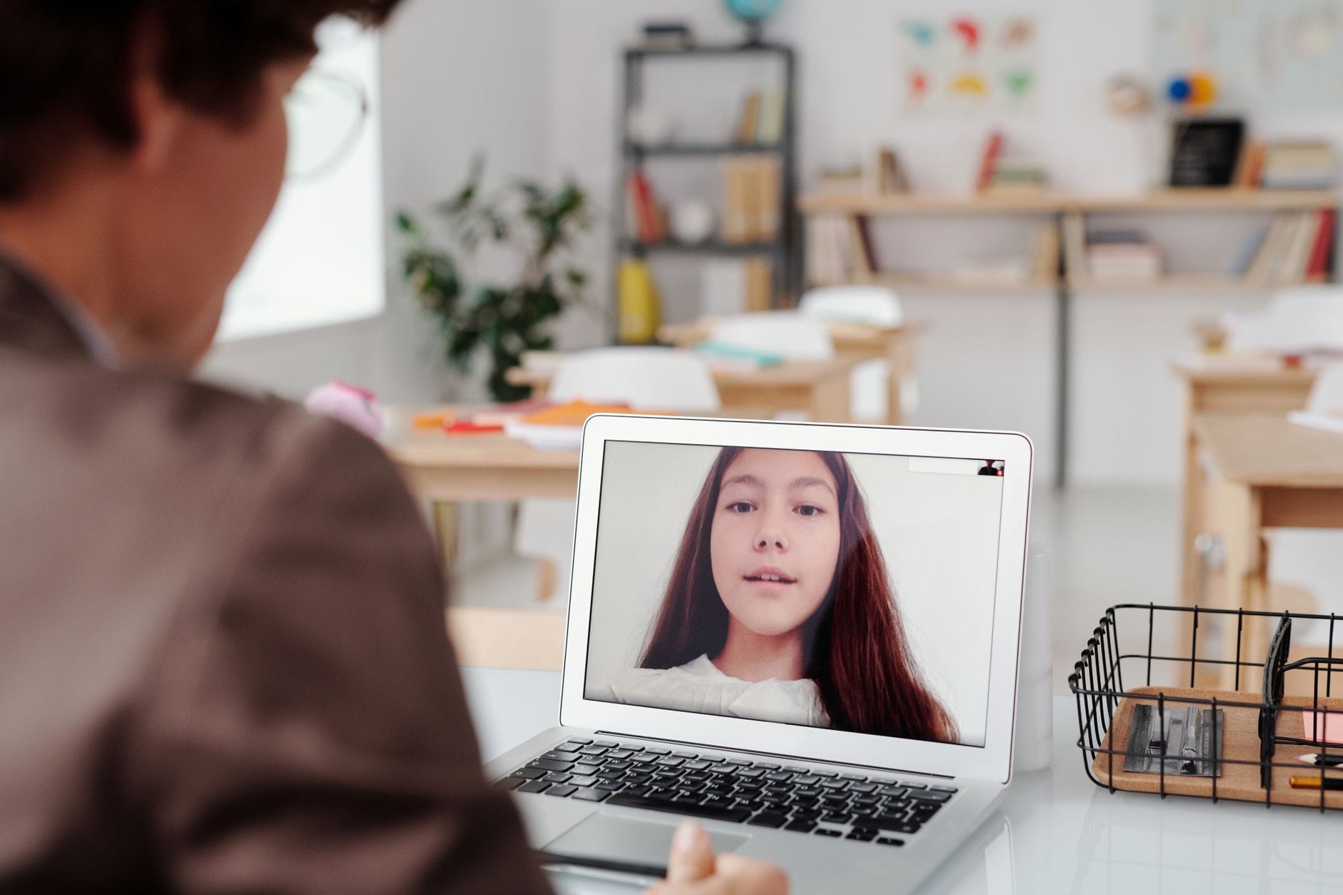 Nauczyciel prowadzi lekcję online z uczennicą na ekranie laptopa