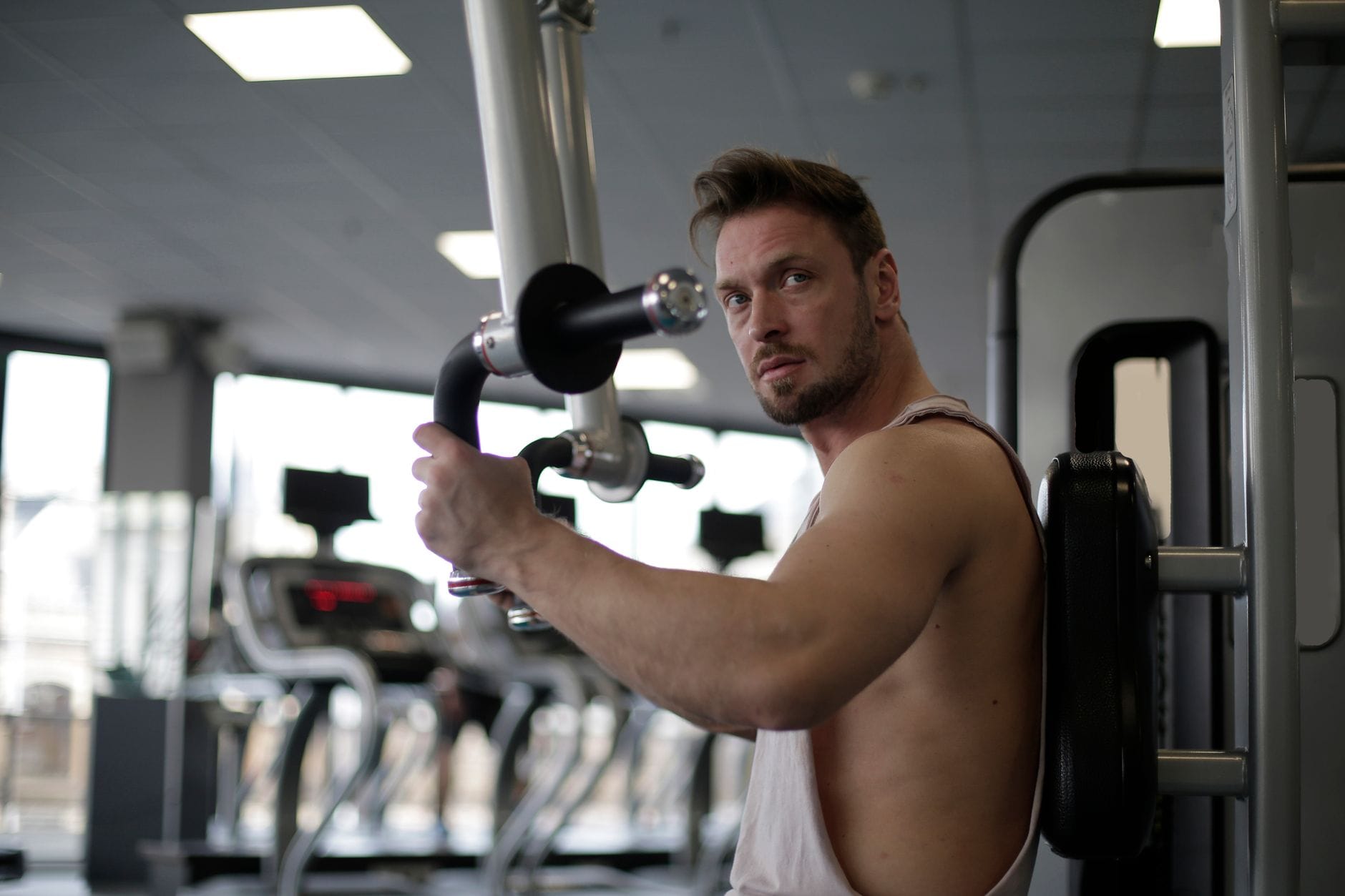 Skupiony mężczyzna trenuje biceps na siłowni podczas intensywnego wysiłku