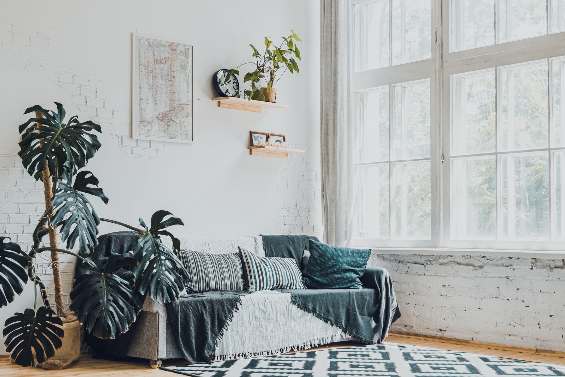 Jasny salon w bloku z plakatem na ścianie, roślinami i wygodną sofą