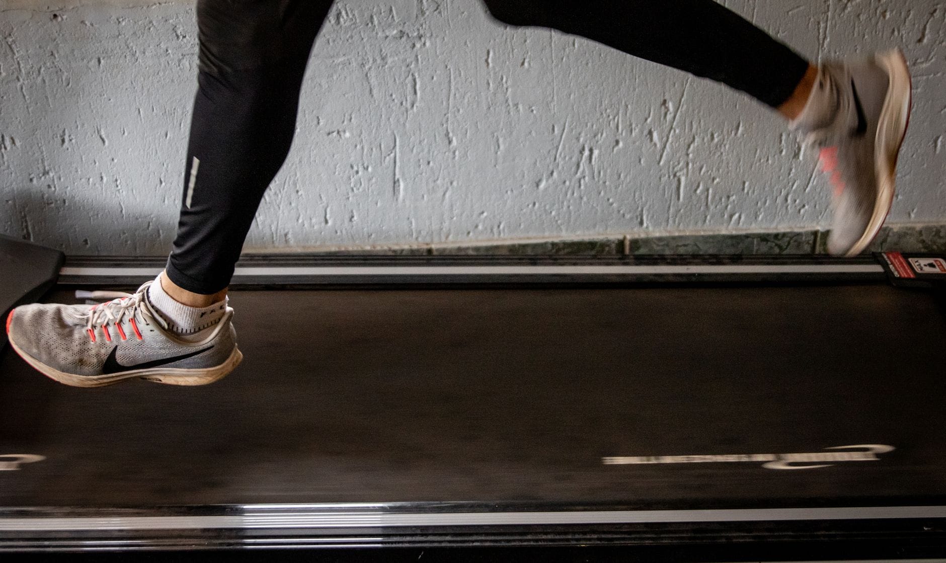 Kobieta biegnąca na bieżni w trakcie treningu cardio indoors