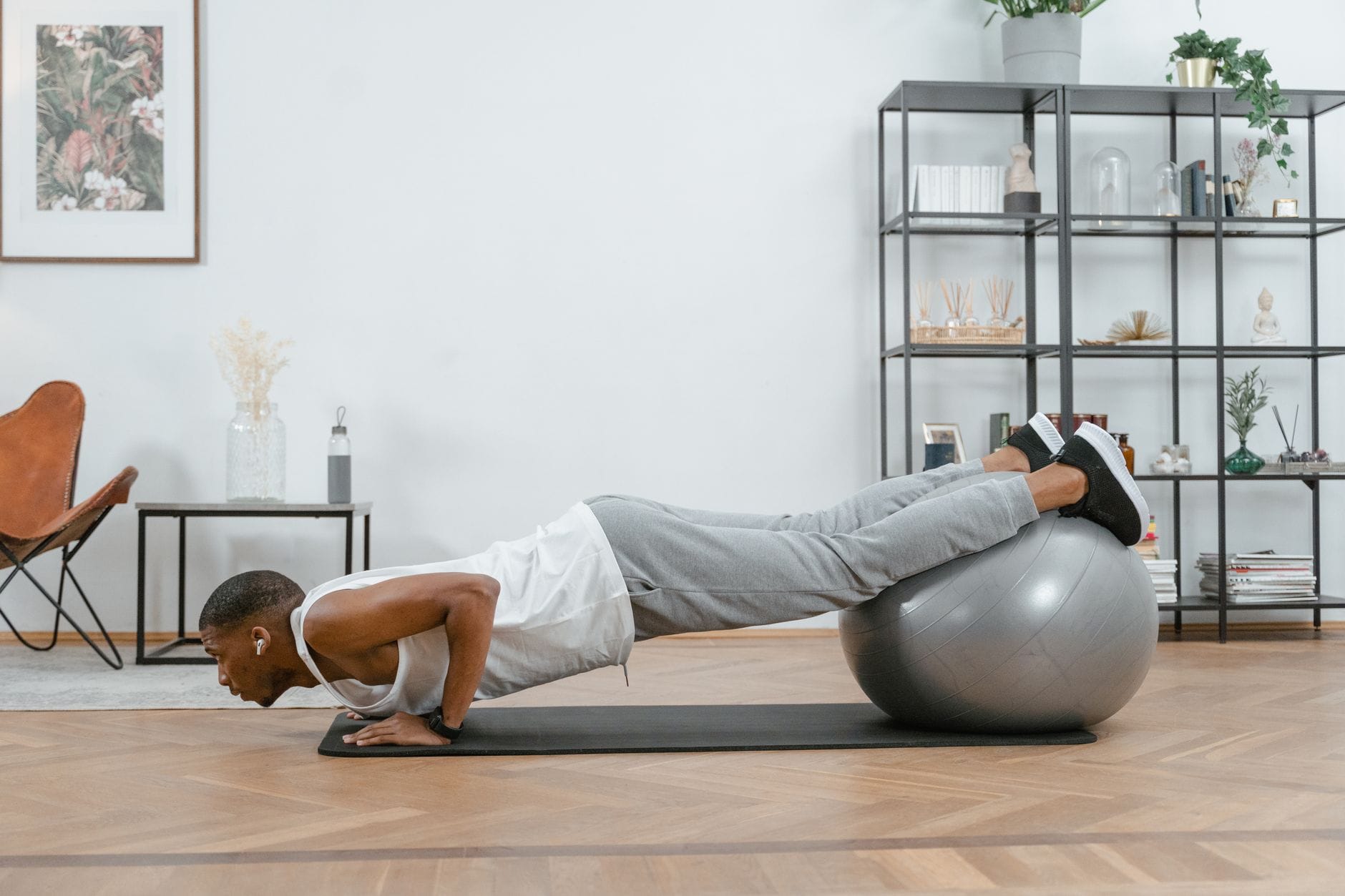 Mężczyzna robi pompki w domu z nogami opartymi na piłce fitness