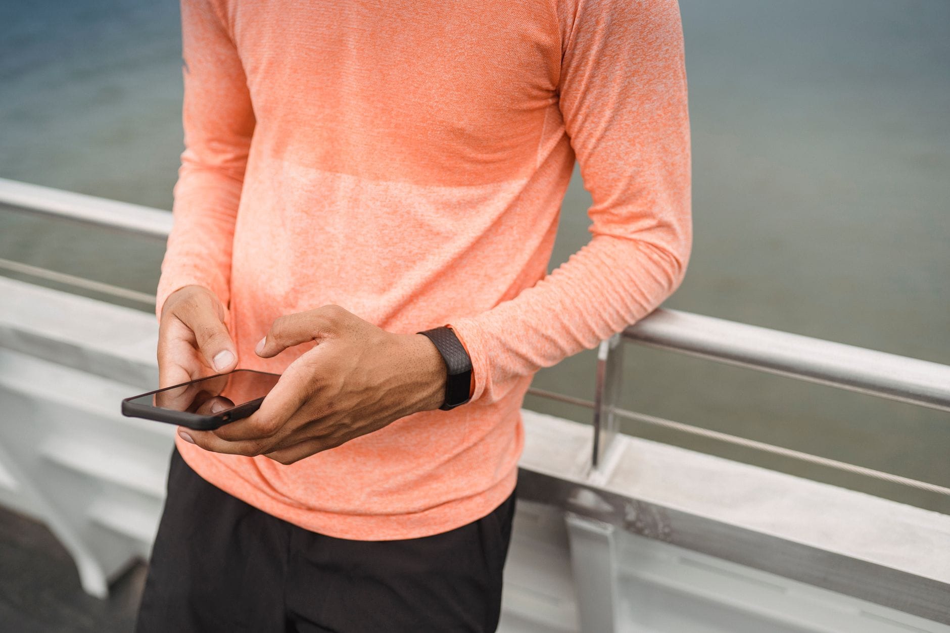 Mężczyzna w sportowym stroju sprawdza telefon po treningu na dworze