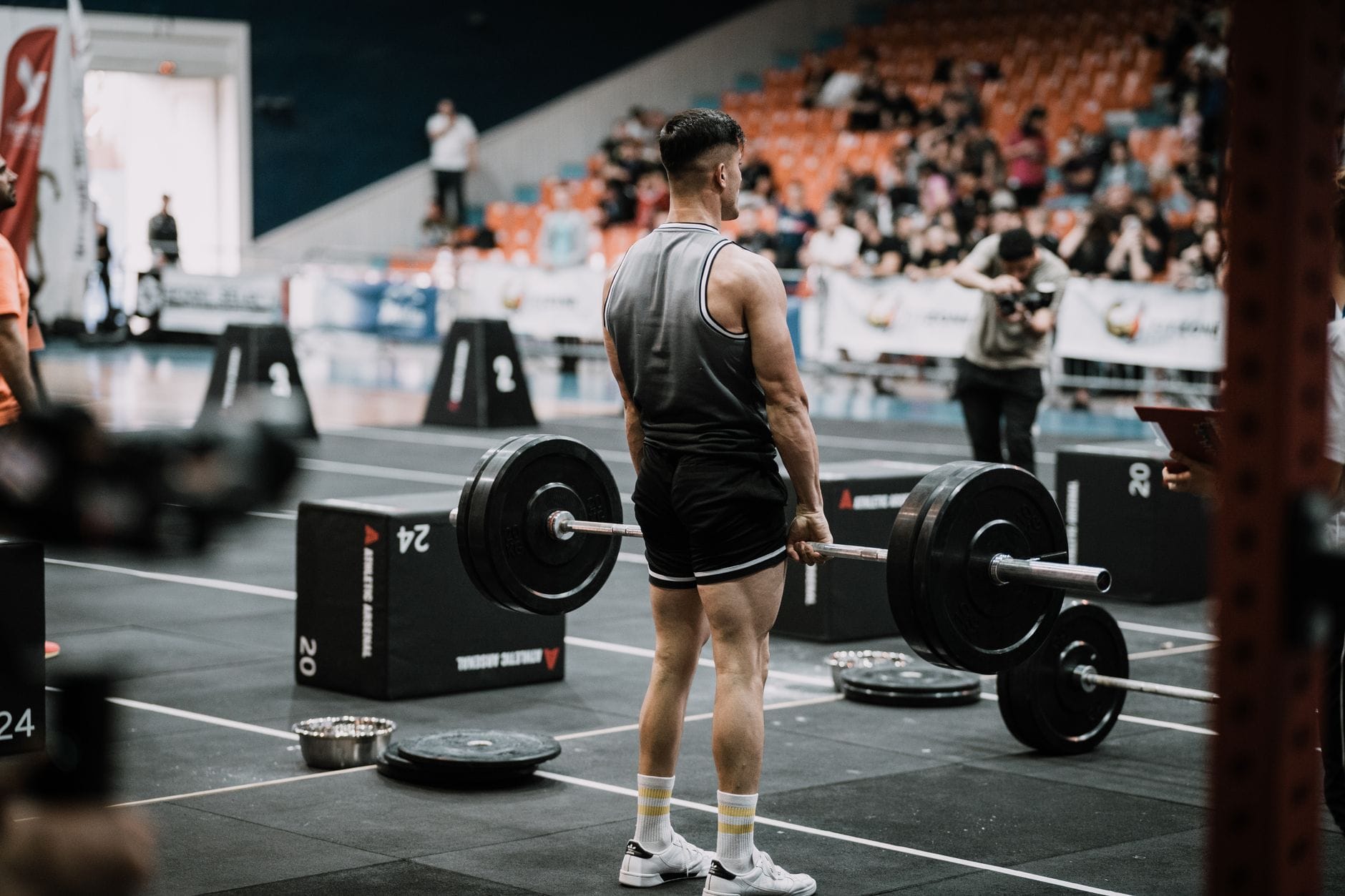 Młody mężczyzna podnosi ciężary na hali sportowej podczas zawodów