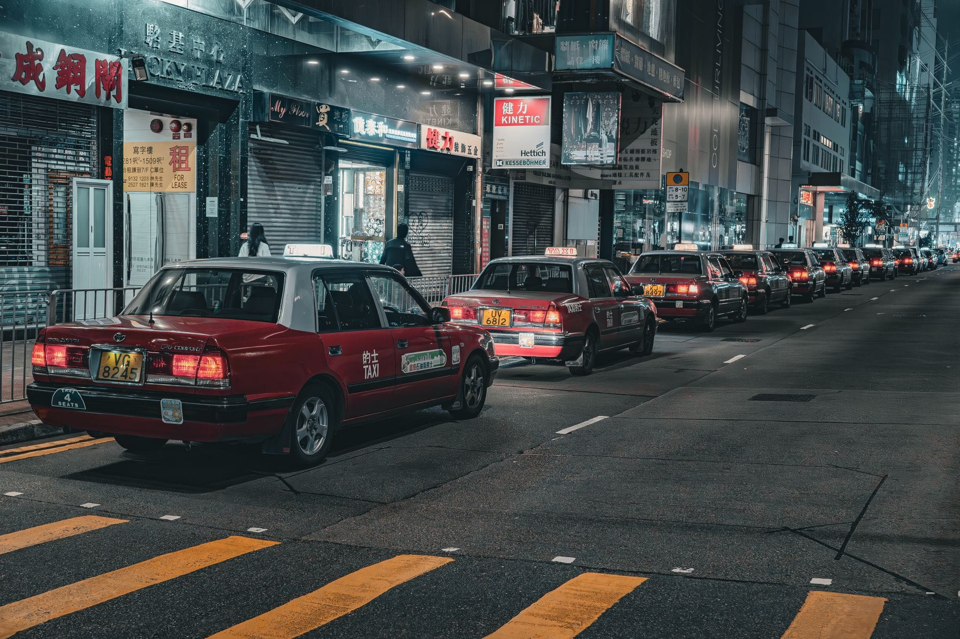 Nocna ulica Hongkongu z szeregiem czerwonych taksówek