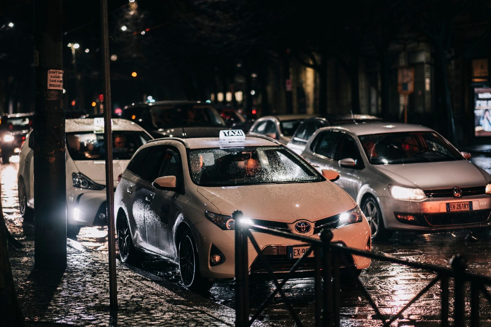 Nocna ulica w deszczu z taksówkami i odbiciami miejskich świateł